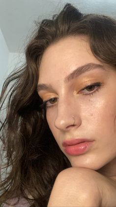 a woman with brown hair and gold eyeshadow is posing for the camera while she has her hand on her shoulder