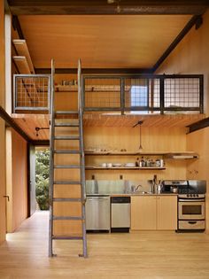 an open kitchen with stairs leading to the upper floor and second story above it is a stainless steel stove top oven