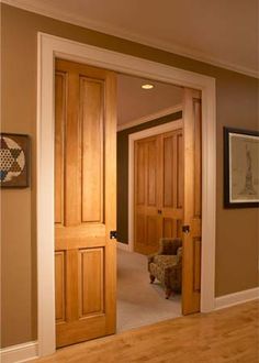 an open door leading to a living room with a chair and pictures on the wall