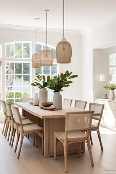 a dining room table and chairs with plants in vases on the top one side