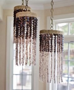 two chandeliers with beads hanging from them in front of a window and windowsill