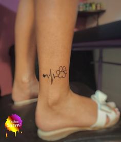 a dog paw and heartbeat tattoo on the ankle