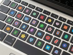 an open laptop computer with colorful stickers on the keyboard and mouse pad, all in different shapes and sizes