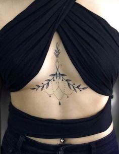 a woman's lower back tattoo with leaves and beads on her ribs, which is covered in black fabric