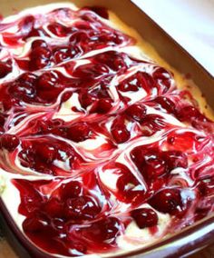 an uncooked dish with cherries and cream in it