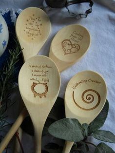 four wooden spoons with engraved designs on them and some plants in the foreground