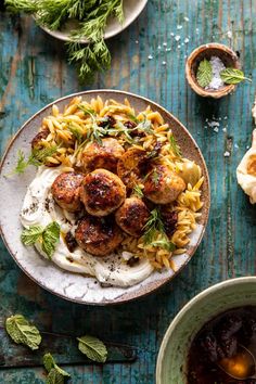 pasta with meatballs and sauce in a bowl on a blue wooden table next to other dishes