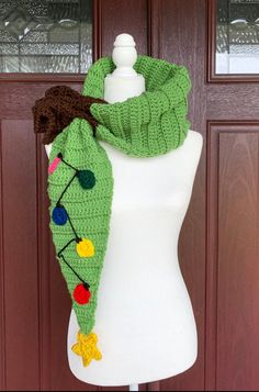 a white mannequin wearing a green scarf with pom poms on it