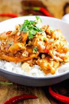 a white bowl filled with rice covered in chicken and sauce on top of a wooden table