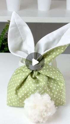 a green bag with white polka dots and a bow on the top that has a pom - pom attached to it