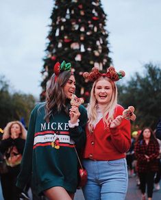 two women walking down the street in front of a christmas tree with donuts on their heads