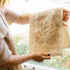 a woman holding up a piece of cloth with writing on it