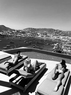 two women lounging on chaise lounges at the top of a hill overlooking a city