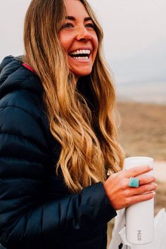 a woman holding a coffee cup and smiling