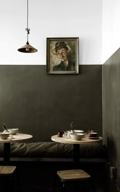 two tables with plates and cups on them in front of a painting hanging from the wall