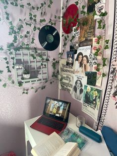 a laptop computer sitting on top of a white desk next to a wall covered in pictures