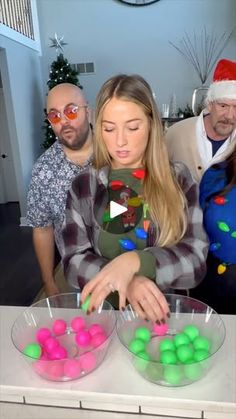 a group of people standing around a table with bowls of balls in front of them