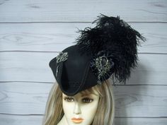 Ladies black woolen MINI pirate hat with black ostrich feathers on the left side of the hat, black cocarde with a large sparkly jewel, metal octopus charm with a pirate charm dangle.  There is an elastic strap that goes under your hair at the nape of your neck. This hat is more of a 3/4 size hat that sits on top of your head and not down on your head like a regular hat. The hat measures about 11"x10" wide. The inside circumference is 21" All sales are FINAL, no returns or exchanges please keep this in mind before purchasing. Please let me know if you have any questions International buyers: Please know that you will be held responsible for any CUSTOMS FEES. Please check with you local post office, before ordering to see what the customs fee rate is before you purchase Pirate Hat Women Feathers, Pirate Hat Fancy, Pirate-style Brimmed Costume Hat, Black Pirate Costume Hat With Curved Brim, Black Costume Top Hat With Short Brim, Black Top Hat With Short Brim For Costume, Black Brimmed Top Hat For Costume, Gothic Black Brimmed Hat, Black Short Brim Top Hat For Costume