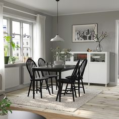 a dining room table and chairs in front of a window with potted plants on it