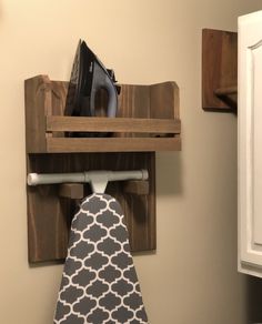 an ironing board mounted to a wall with a tie hanging from it's holder