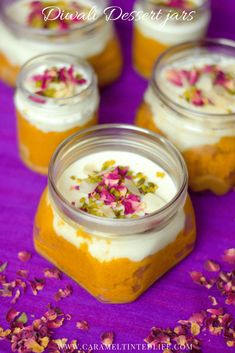 four jars filled with food sitting on top of a purple tablecloth covered in petals