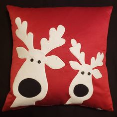 a red and white pillow with two reindeer faces on it's sides, both facing each other