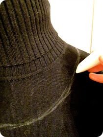 a person holding an object in their right hand while wearing a black sweater and orange nails