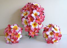 pink and yellow flowers are arranged on a white counter top, next to each other