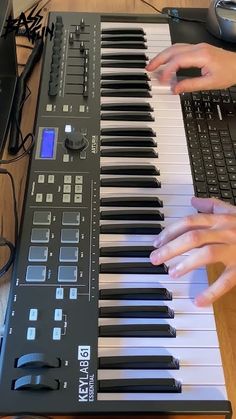 a person playing an electronic keyboard with their hands on the keys and mouse beside it