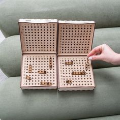 two pieces of perforated cardboard with holes in them being held by a person's hand