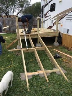 two men working on building a house in the yard with a dog and trailer behind them