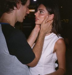 a man and woman standing next to each other in front of a building at night