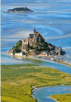 an island in the middle of water with a castle on it's top and other land