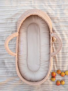 an empty crocheted baby bed with some fruit on the ground next to it