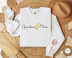 a white shirt with the words grandma bear on it and a straw hat next to it