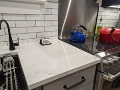 a stove top oven sitting inside of a kitchen next to a tea kettle and pan