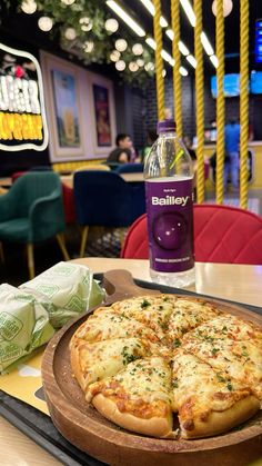 a pizza sitting on top of a wooden cutting board next to a bottle of booze