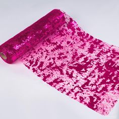 a roll of pink sequinized fabric sitting on top of a white surface