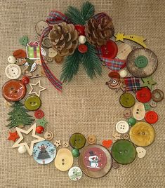 a christmas wreath made out of buttons and pine cones on a burlap background