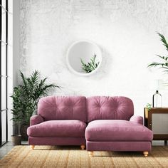 a living room with a pink couch and potted plants on the side table next to it