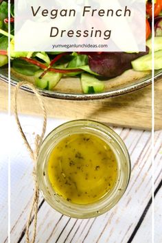 a glass jar filled with dressing sitting on top of a table next to a salad