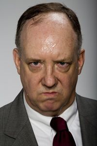 a man in a suit and tie looking at the camera with an angry look on his face