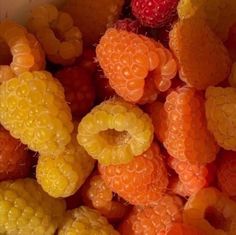 raspberries and other fruits are shown in this close up photo, including oranges, yellows, and strawberries