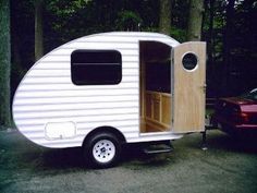 a small white trailer parked next to a red car