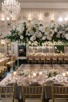 an elegant wedding reception with tall centerpieces and white flowers on the top table