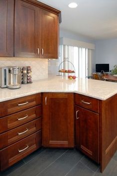 a kitchen with wooden cabinets and white marble counter tops, along with stainless steel appliances