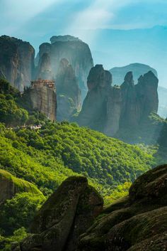 the mountains are covered in green vegetation and rocks, with trees on each one side