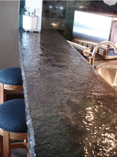 a kitchen counter with two stools next to it and a tv on the wall