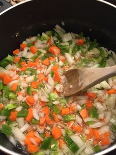 vegetables being cooked in a pot with a wooden spoon on the stove top, ready to be eaten