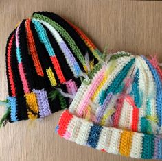 three crocheted hats are laying next to each other on the floor, one is multicolored